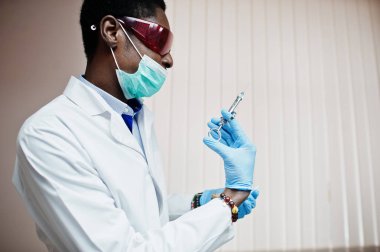 Afrika kökenli Amerikalı Doktor tıbbi maskesi ve kırmızı gözlük şırınga enjeksiyon için hazır. 