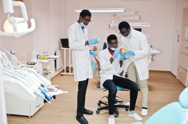 Üç Afro-Amerikan erkek doktorlar meslektaşları bir elma ile diş kliniği. 