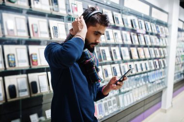 Hint sakallı adam müşteri alıcı cep telefonu mağaza dinle müzik radyo earphones, onun Smartphone-e doğru bağlamak. Güney Asya halkları ve teknolojileri kavramı. Cep Telefonu Dükkanı.