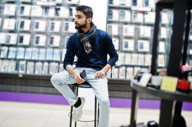 Hint sakallı adam müşteri alıcı ile smartphone el altında sandalyede oturan cep telefonu mağazasında. Güney Asya halkları ve teknolojileri kavramı. Cep Telefonu Dükkanı.