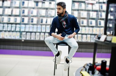 Hint sakallı adam müşteri alıcı ile smartphone el altında sandalyede oturan cep telefonu mağazasında. Güney Asya halkları ve teknolojileri kavramı. Cep Telefonu Dükkanı.