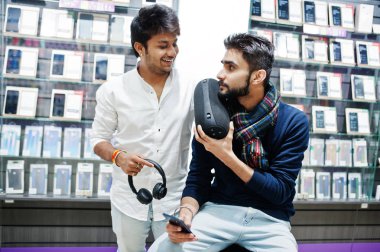 İki Hintliler müşteri alıcı earphones ve kablosuz hoparlör dinleme müzik ile cep telefonu mağazasında mans. Güney Asya halkları ve teknolojileri kavramı. Cep Telefonu Dükkanı.