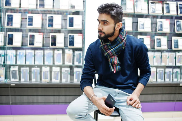 Hint sakallı adam müşteri alıcı ile smartphone el altında sandalyede oturan cep telefonu mağazasında. Güney Asya halkları ve teknolojileri kavramı. Cep Telefonu Dükkanı.