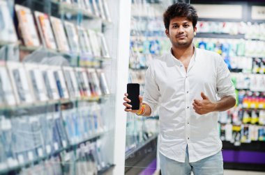 Hintli müşteri alıcı cep telefonu mağazasında onun yeni smartphone seçmek ve başparmak sırıtmak. Güney Asya halkları ve teknolojileri kavramı. Cep Telefonu Dükkanı.