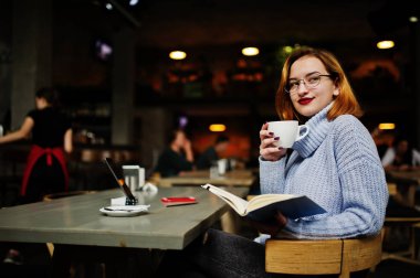 Neşeli genç güzel redhaired kadın gözlük Cafe kahve ile üzerinde çalışma evinde otururken ona telefon, dokunmatik yüzey ve dizüstü bilgisayar kullanarak.