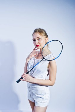 İnanılmaz fit seksi vücut esmer beyaz kız şort ve üst beyaz arka planı stüdyosunda badminton raket ile poz.
