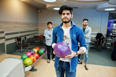 Kot gömlek ayakta eller üzerinde topu ile bowling salonu, Güney Asya adam. Adam bir atmak için hazırlanıyor. Arkadaşları ona destek.
