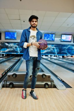 Şık sakal Asya adam kot gömlek ayakta el topu ile bowling salonu.