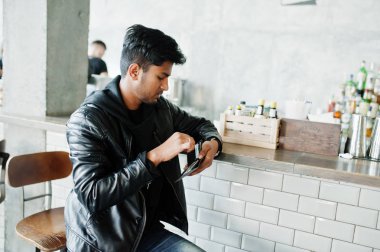 Rahat ve şık genç Asyalı adam Giyim deri ceket oturan bar ve cüzdanını arıyorsunuz.