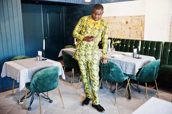 Vriendelijke afro mens in traditionele gele kleren bij restaurant, m — Stockfoto