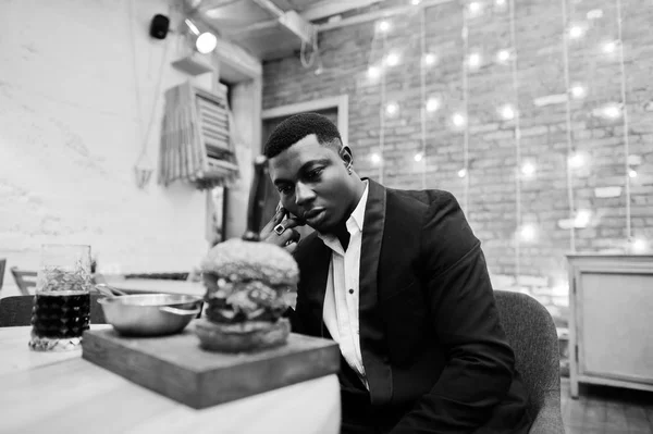 Respektabler junger afrikanisch-amerikanischer Mann im schwarzen Anzug sitzt in — Stockfoto