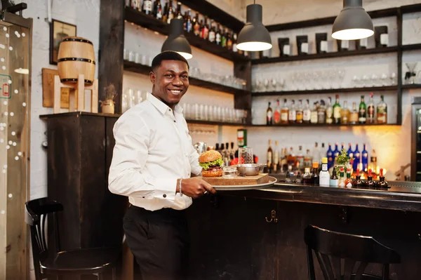 Young african american waiter man hold tray with burger at bar o