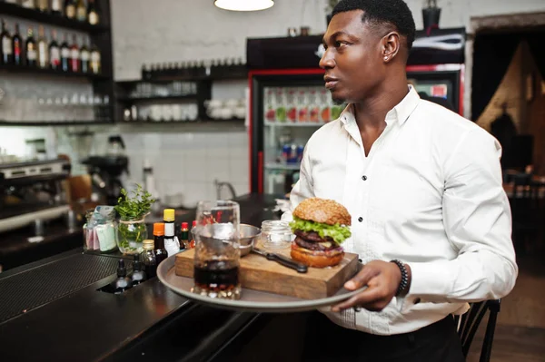 Young african american waiter man hold tray with burger at bar o