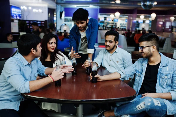Groep van stijlvolle Aziatische vrienden slijtage op jeans zitten aan tafel een — Stockfoto