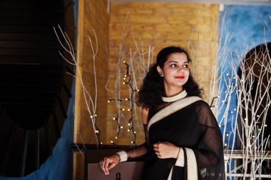 Genç Hint kadın Wear at zarif siyah Saree PoseD üzerinde kafeterya