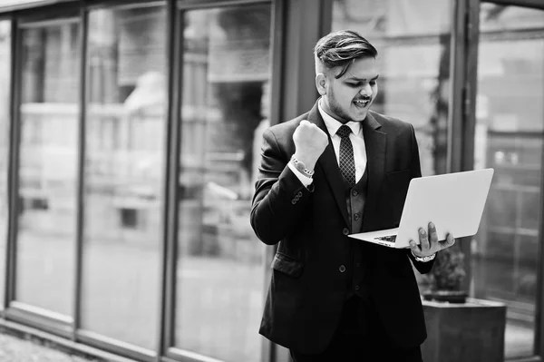 Stylish excited happy indian businessman in formal wear with lap