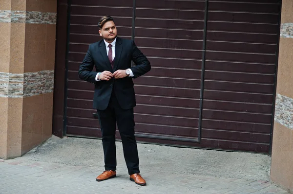 Homem de negócios indiano elegante em desgaste formal em pé contra marrom — Fotografia de Stock