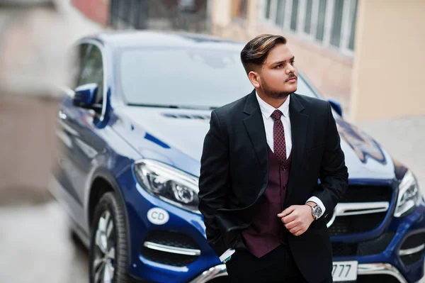 Rich indian businessman in formal wear standing against business — Stock Photo, Image