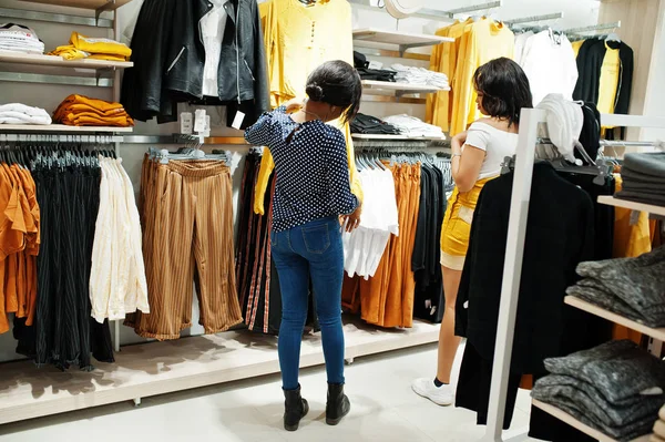 Zwei Afrikanerinnen, die Kleidung im Geschäft aussuchen. Einkaufstag. — Stockfoto