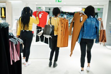 Geri üç Afrikalı kadın mağazasında giysiler seçmek. Alışveriş 