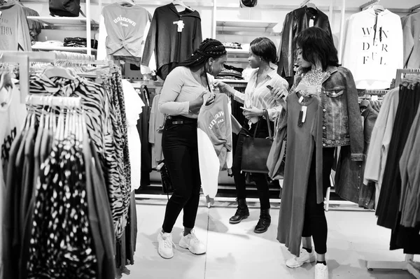 Três africanas escolhendo roupas na loja. Dia de compras . — Fotografia de Stock