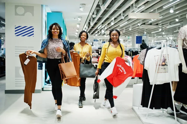 Three african woman choosing clothes at store. Shopping day.