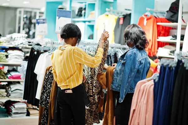 Zwei Afrikanerinnen, die Kleidung im Geschäft aussuchen. Einkaufstag. — Stockfoto