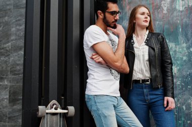 Longboard ile duvara poz Cool ırklararası çift.