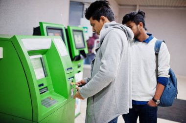İki Asya çocuklar kaldırır nakit itibaren bir yeşil ATM.