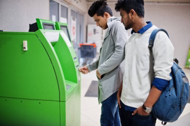 İki Asya çocuklar kaldırır nakit itibaren bir yeşil ATM.