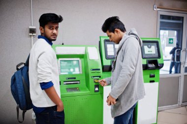 İki Asya çocuklar kaldırır nakit itibaren bir yeşil ATM.