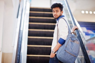 Genç Asya adam ile Backpack hamle üzerinde yürüyen merdiven at Mall.