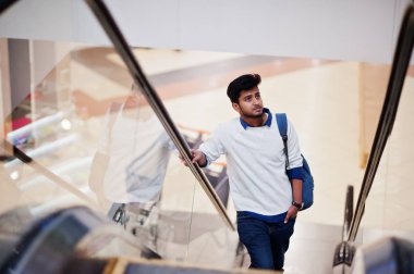 Genç Asya adam ile Backpack hamle üzerinde yürüyen merdiven at Mall.