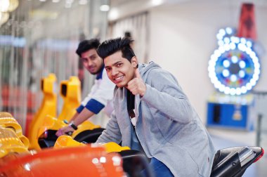 İki Asyalı adamlar hız binici arcade oyun motosiklet RAC üzerinde rekabet