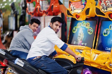 İki Asyalı adamlar hız binici arcade oyun motosiklet RAC üzerinde rekabet
