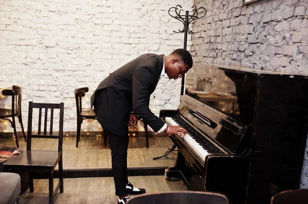Starker afrikanischer Amerikaner im schwarzen Anzug spielt Klavier. — Stockfoto