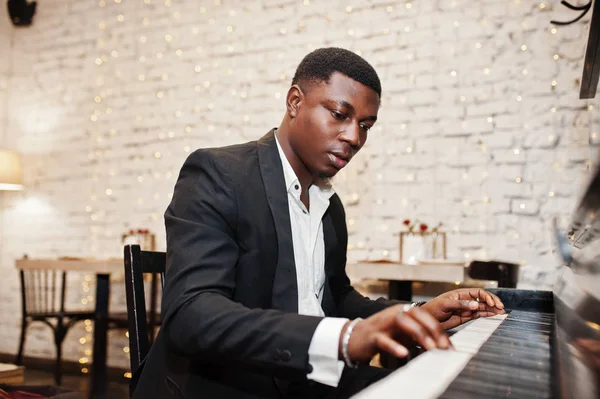 Strong powerful african american man in black suit play piano.