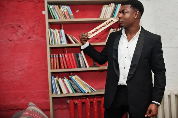 Starker afrikanisch-amerikanischer Mann im schwarzen Anzug gegen Buch — Stockfoto