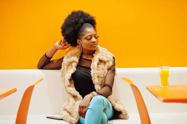 Afrikansk kvinna sitter på Café mot orange vägg med ananas — Stockfoto