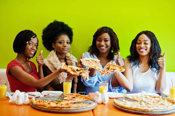 Quatro jovens meninas africanas em restaurante colorido brilhante segurando pi — Fotografia de Stock