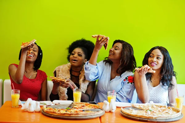 Quatro jovens meninas africanas em restaurante colorido brilhante comendo piz — Fotografia de Stock