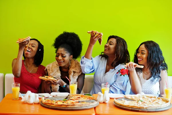 Négy fiatal afrikai lány élénk színű étteremben étkezési Piz — Stock Fotó