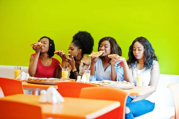 Quatro jovens meninas africanas em restaurante colorido brilhante comendo piz — Fotografia de Stock