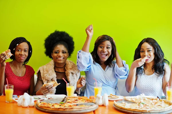 Quatro jovens meninas africanas em restaurante colorido brilhante comendo piz — Fotografia de Stock