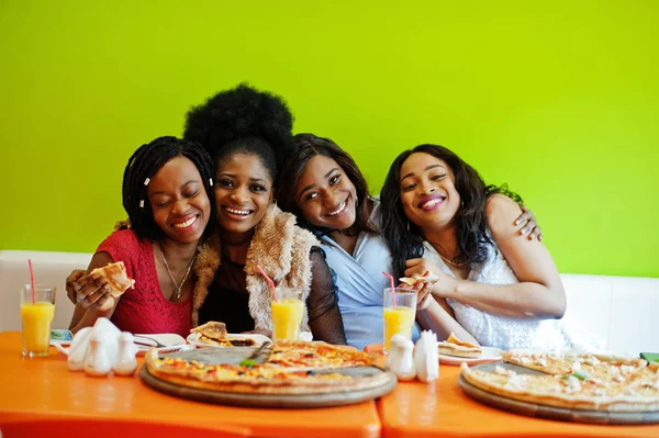 Quatro jovens meninas africanas em restaurante colorido brilhante comendo piz — Fotografia de Stock