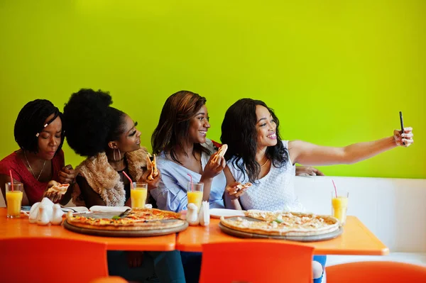 Quatro jovens meninas africanas em restaurante colorido brilhante comendo piz — Fotografia de Stock