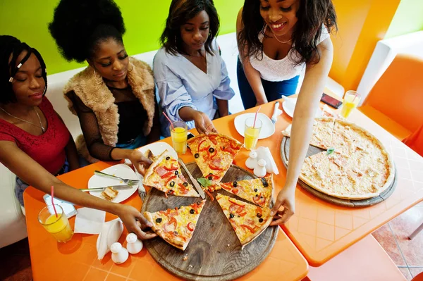Vier junge afrikanische Mädchen in einem farbenfrohen Restaurant beim Piz essen — Stockfoto