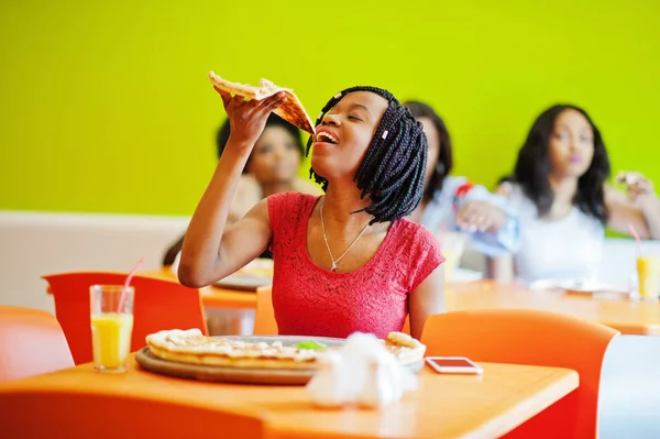 Mulher africana com pizza sentada no restaurante contra a pele escura — Fotografia de Stock