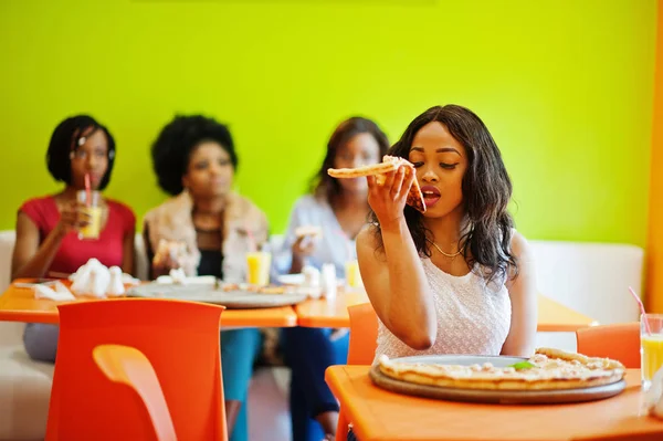 Mulher africana com pizza sentada no restaurante contra a pele escura — Fotografia de Stock