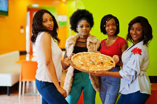 Quatro jovens meninas africanas em restaurante colorido brilhante segurar woode — Fotografia de Stock